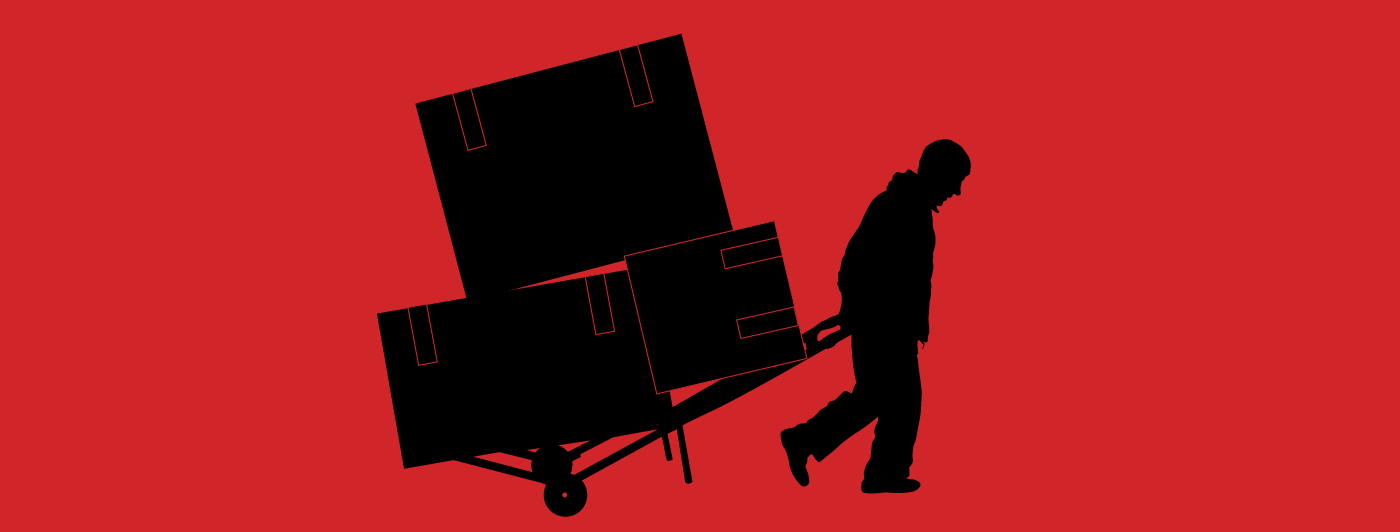 Silhouette of a man carrying three heavy boxes on a hand truck